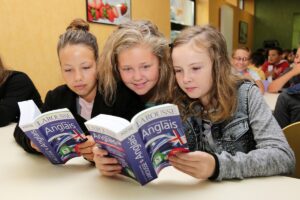 Trois collégiennes découvrant leur livre d'anglais